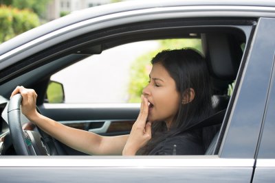 Woman yawning while driving a car