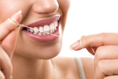 A girl cleaning her teeth with thread