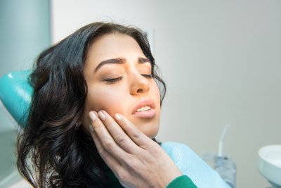 A woman in pain holding his cheek