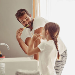 father brushing teeth with daughter